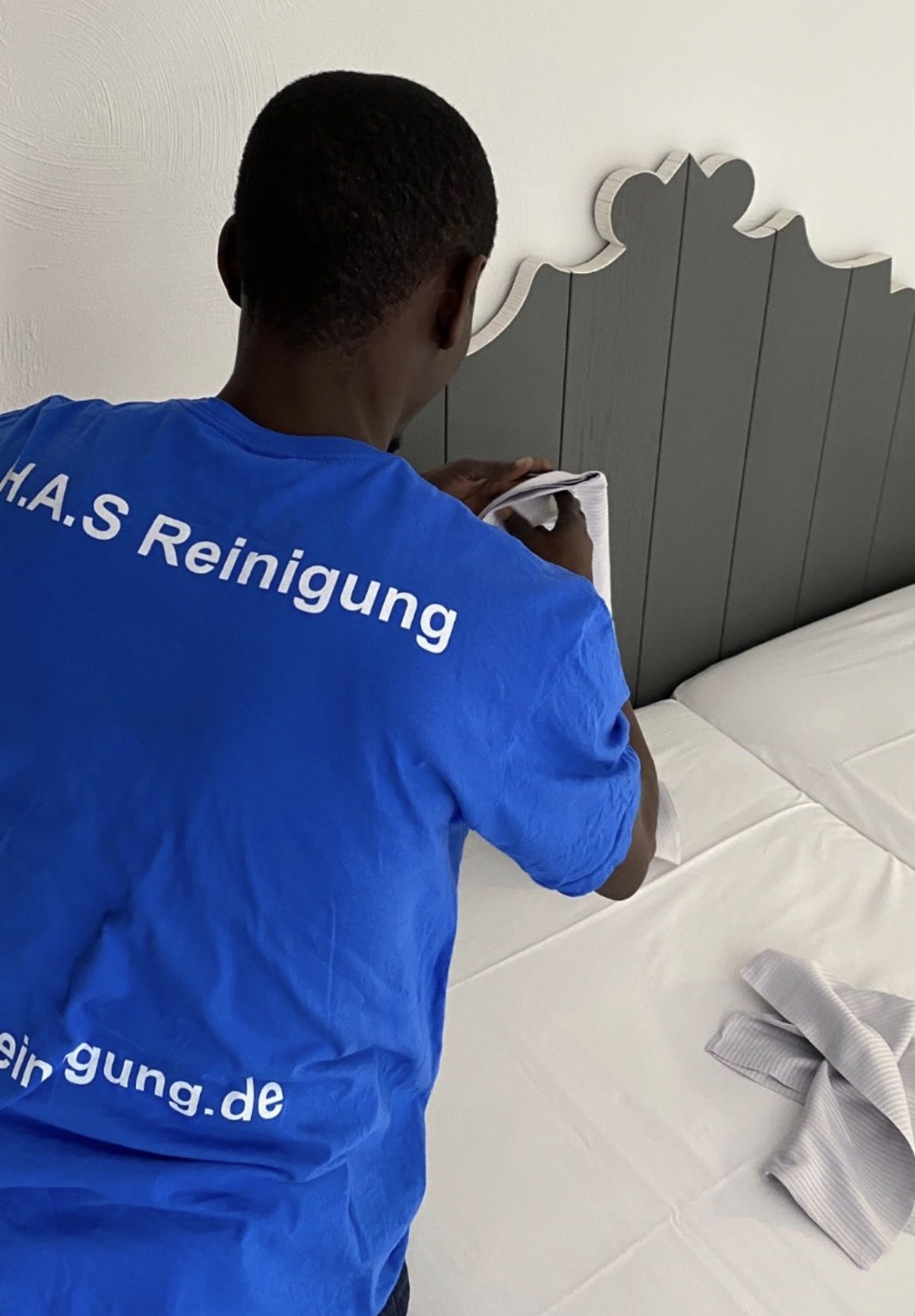 Mitarbeiter von H.A.S Reinigung reinigt das Kopfteil eines Hotelbettes